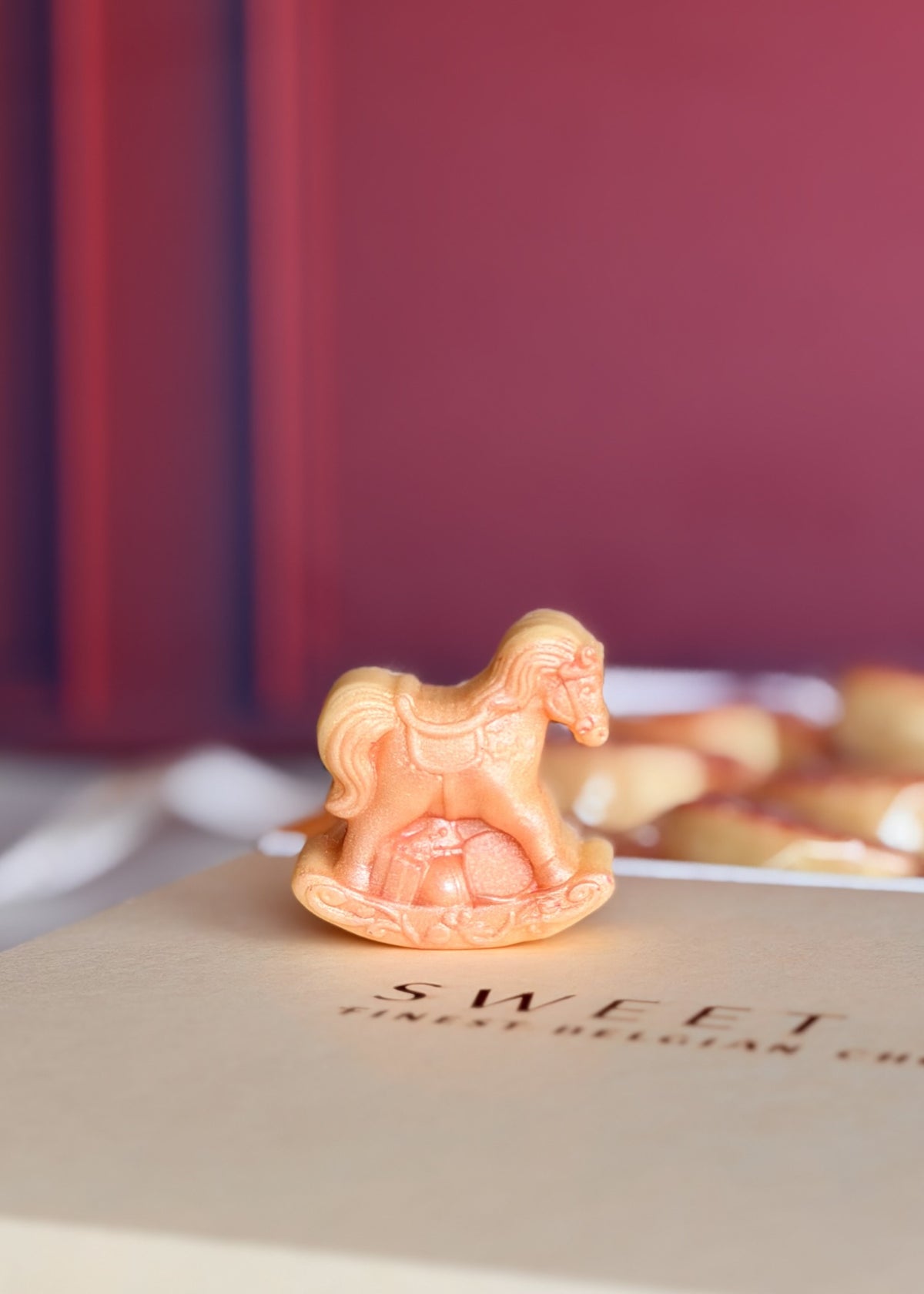 Detalhe de mini cavalinho de balanço de chocolate branco com brilho rosa