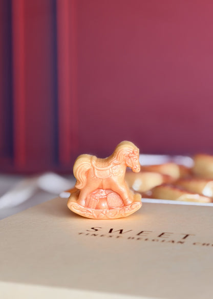 Detalhe de mini cavalinho de balanço de chocolate branco com brilho rosa