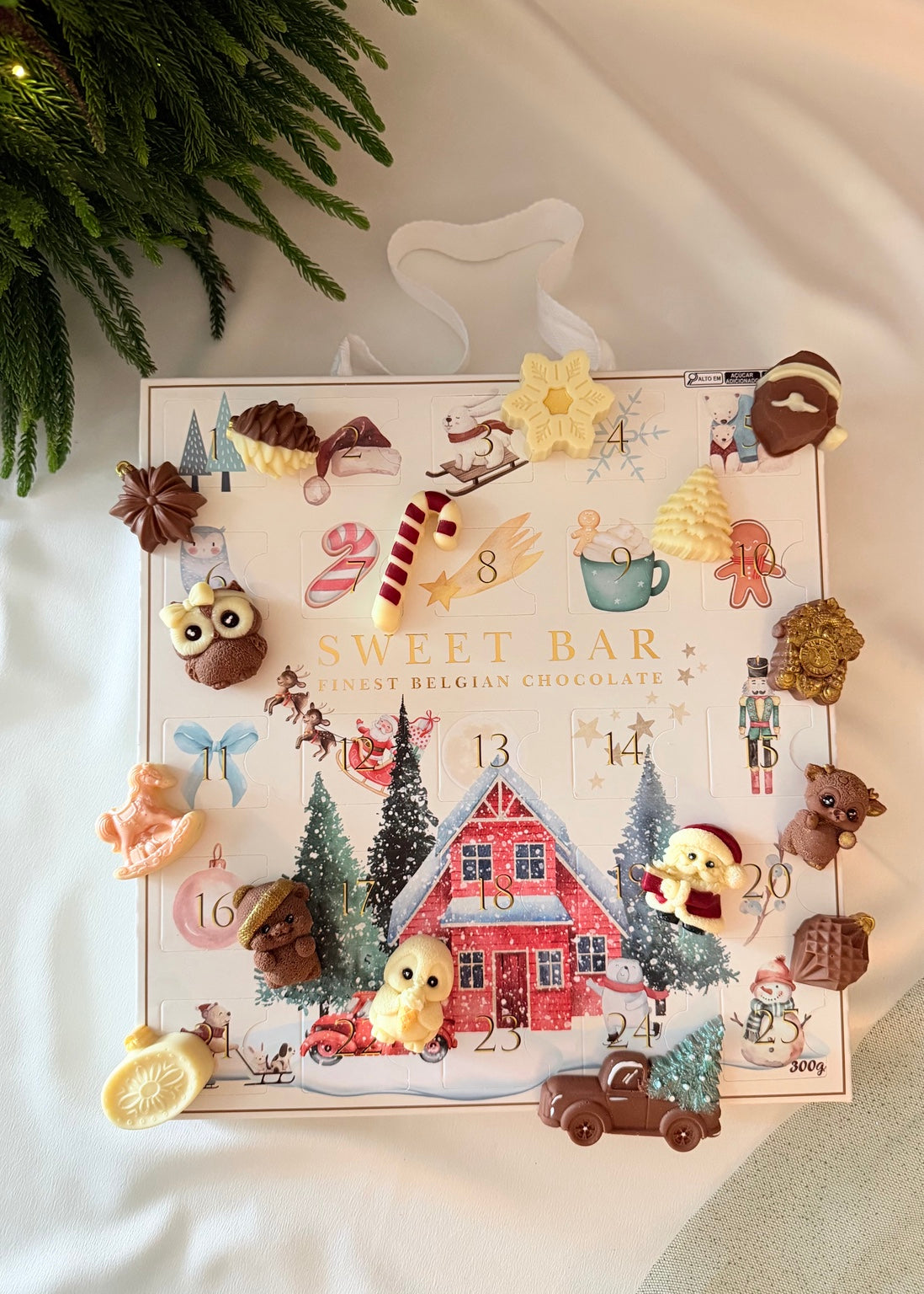 Calendário do Advento Sweet Bar com figurinhas de chocolate ao leite e branco sobre a embalagem natalina.